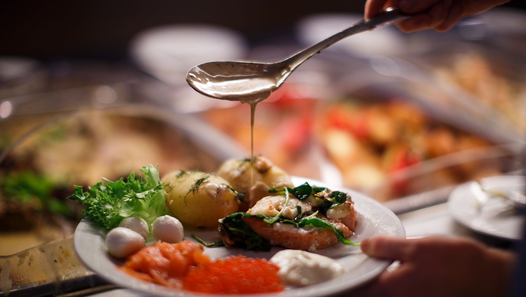 A diner pours sauce onto their plate at Kasnäs Resort.