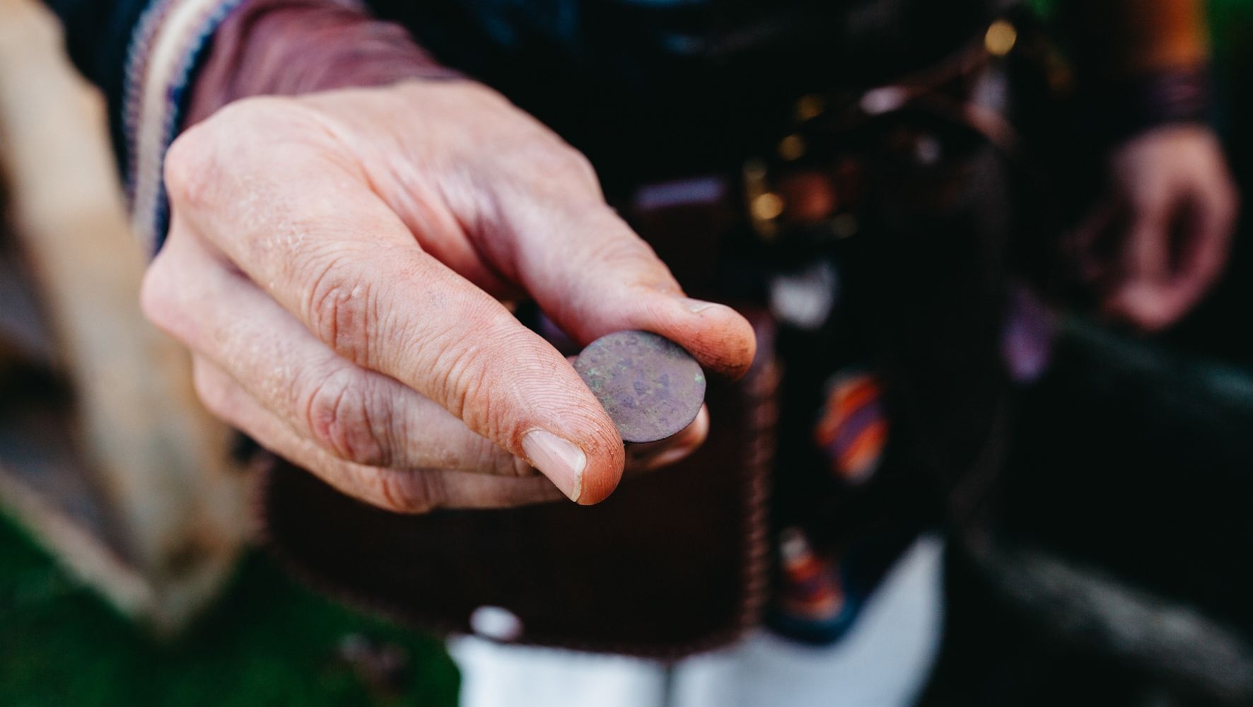 En hand håller fram ett mynt som användes under vikingatiden på Rosala Viking Center.