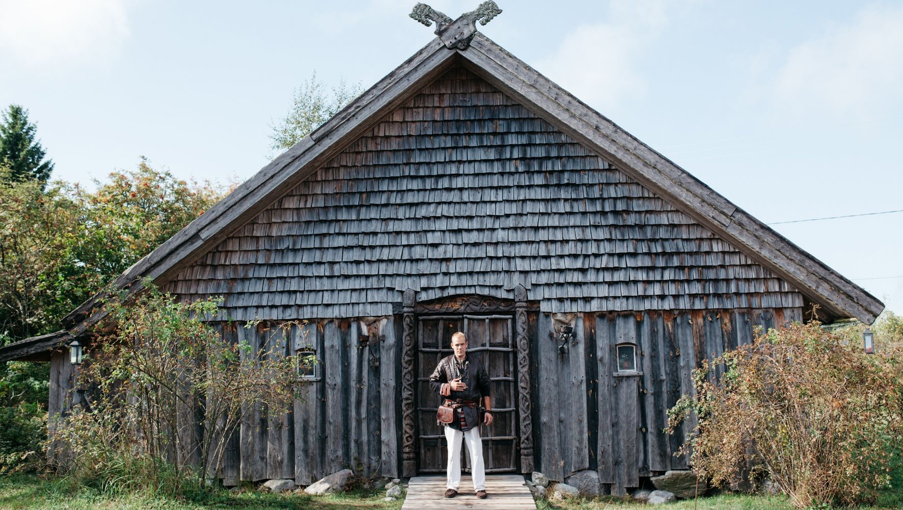 A man dressed in a Viking costume, stands in front of a building at the Rosala Viking Center.