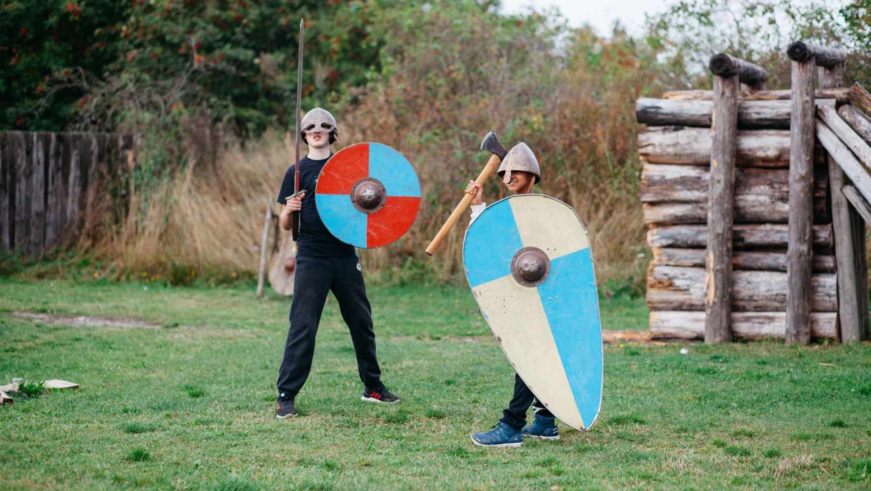 Två barn står på en gräsyta, utklädda till vikingar på Rosala Viking Center.