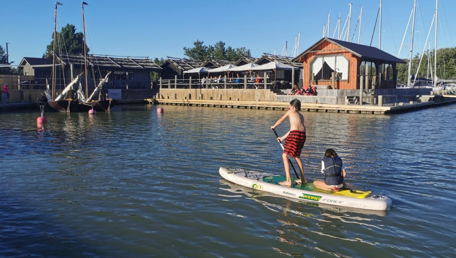 Two people on a SUP board in front of Peterzens.