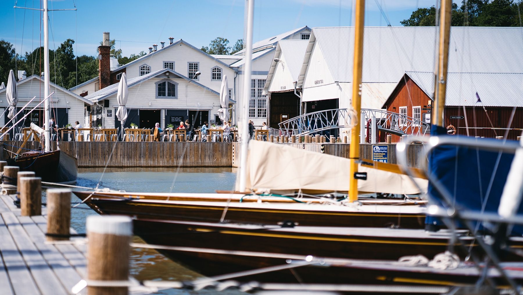 Ruissalo Boatyard en sommardag med båtar som ligger till kaj i hamnen och matgäster som njuter av en måltid på Zake Pizzeria & Wine Bar.