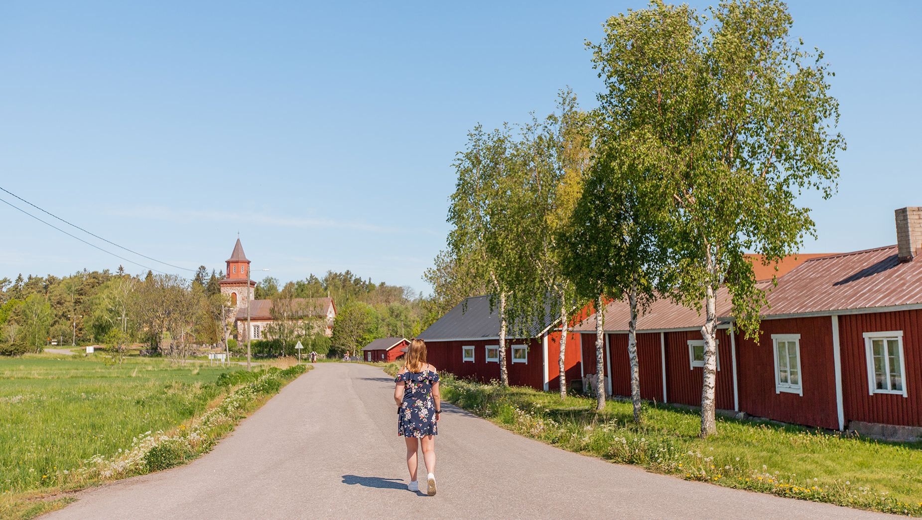 A visitor strolls through Iniö, admiring the church in the distance.