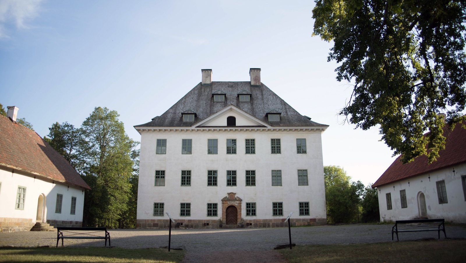 Tre vita byggnader omger en innergård vid Louhisaari herrgård.