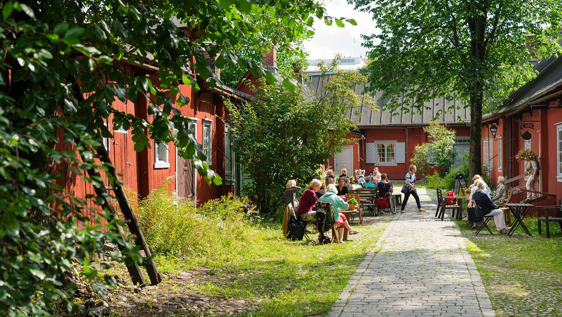 Visitors sit in Cafe Qwensel's outside garden, enjoying coffee and cake.