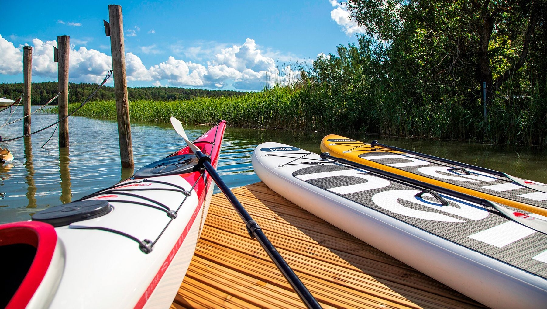 A kayak and two SUP boards on a pier.