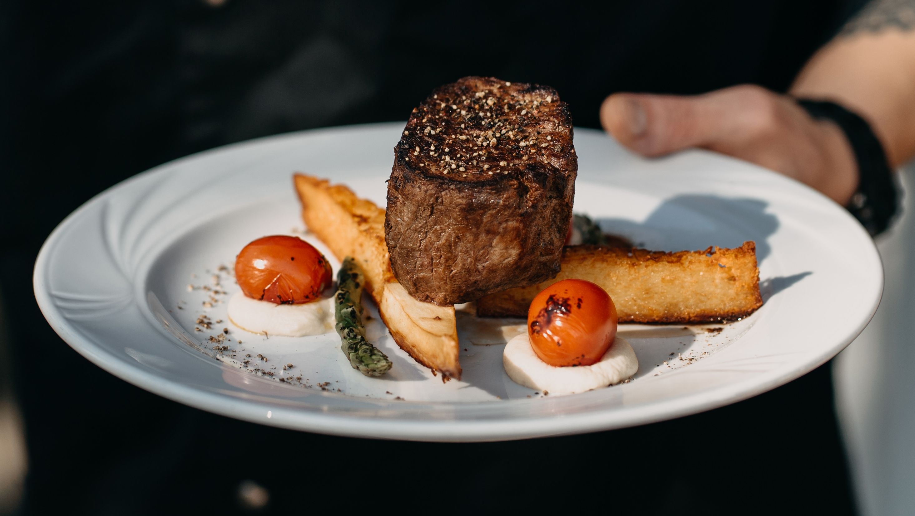 En servitör håller en tallrik med kött och grönsaker på restaurangen Mossala Island Resort.