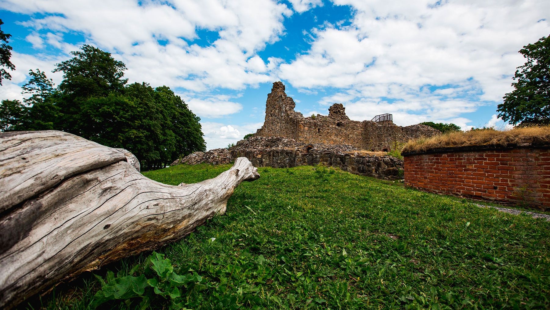 A blue sky dotted with white clouds watches over the Kuusisto Bishop's Castle Ruins, the remains of a once grand building.