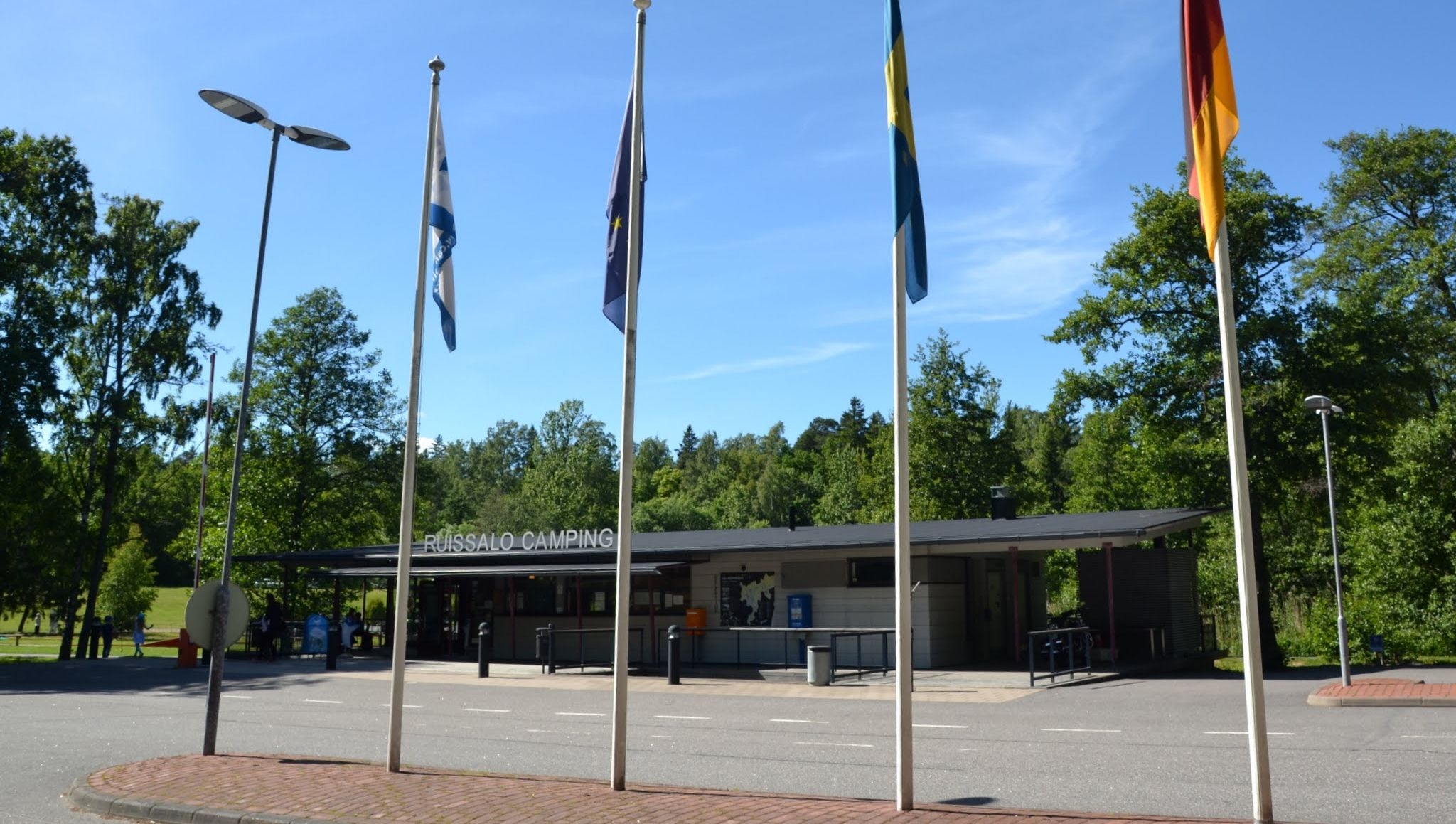 Receptionsbyggnaden på Ruissalo Camping med fyra flaggor som vajar framme.