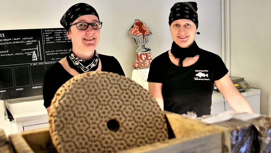 Two women, wearing black uniforms, stand behind the counter at Cafe Holmbergs Four C.