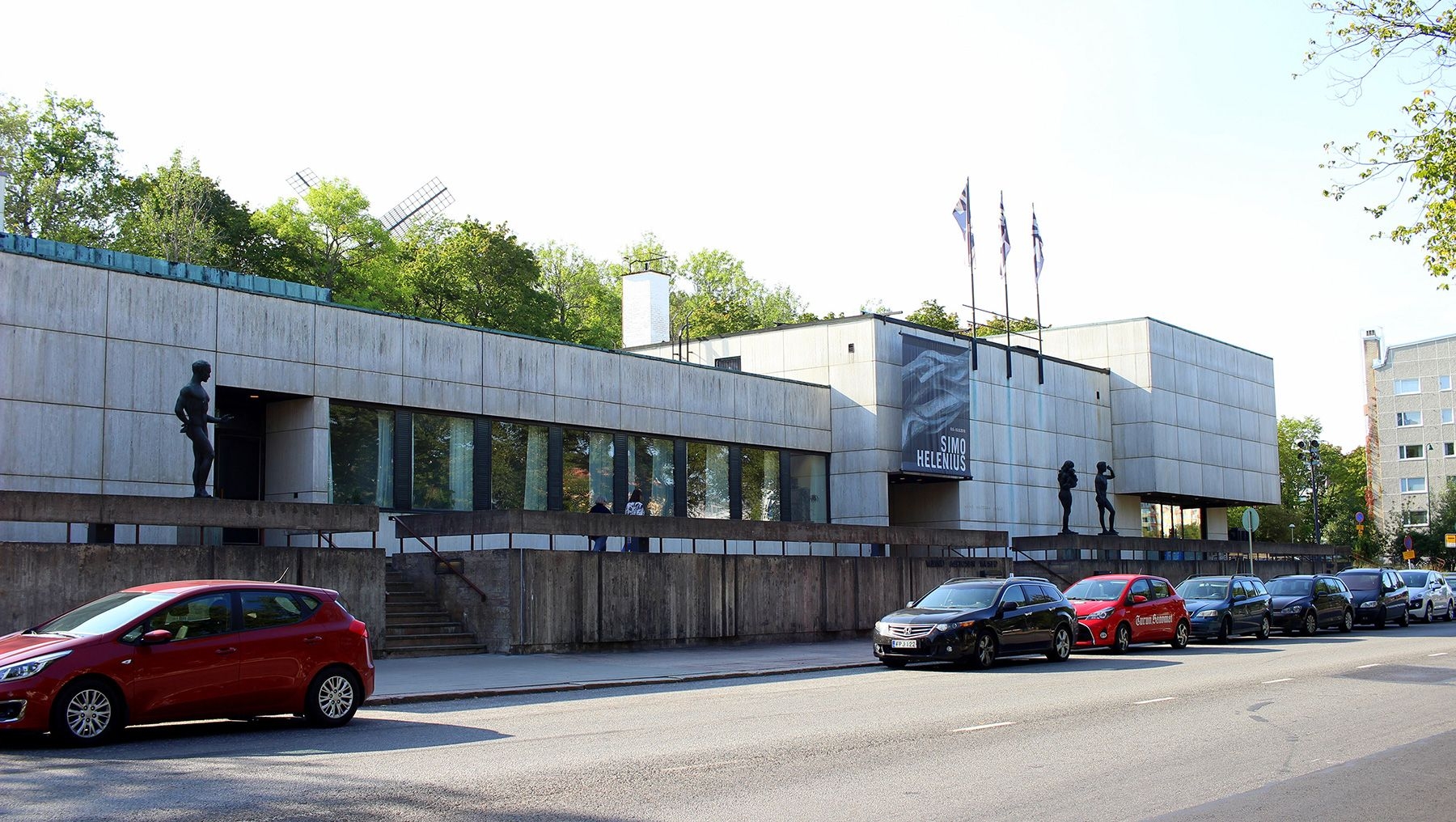 Utsikt från gatan utanför Wäinö Aaltonens museum, kantad av bilar och statyer.