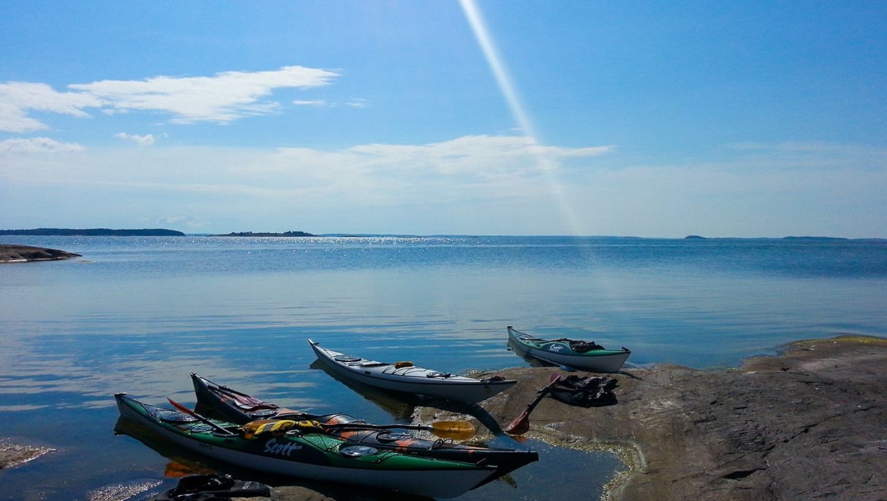 Flera kajaker, som har använts på ett Aavameri utomhusäventyr, vilar på stranden av en ö.