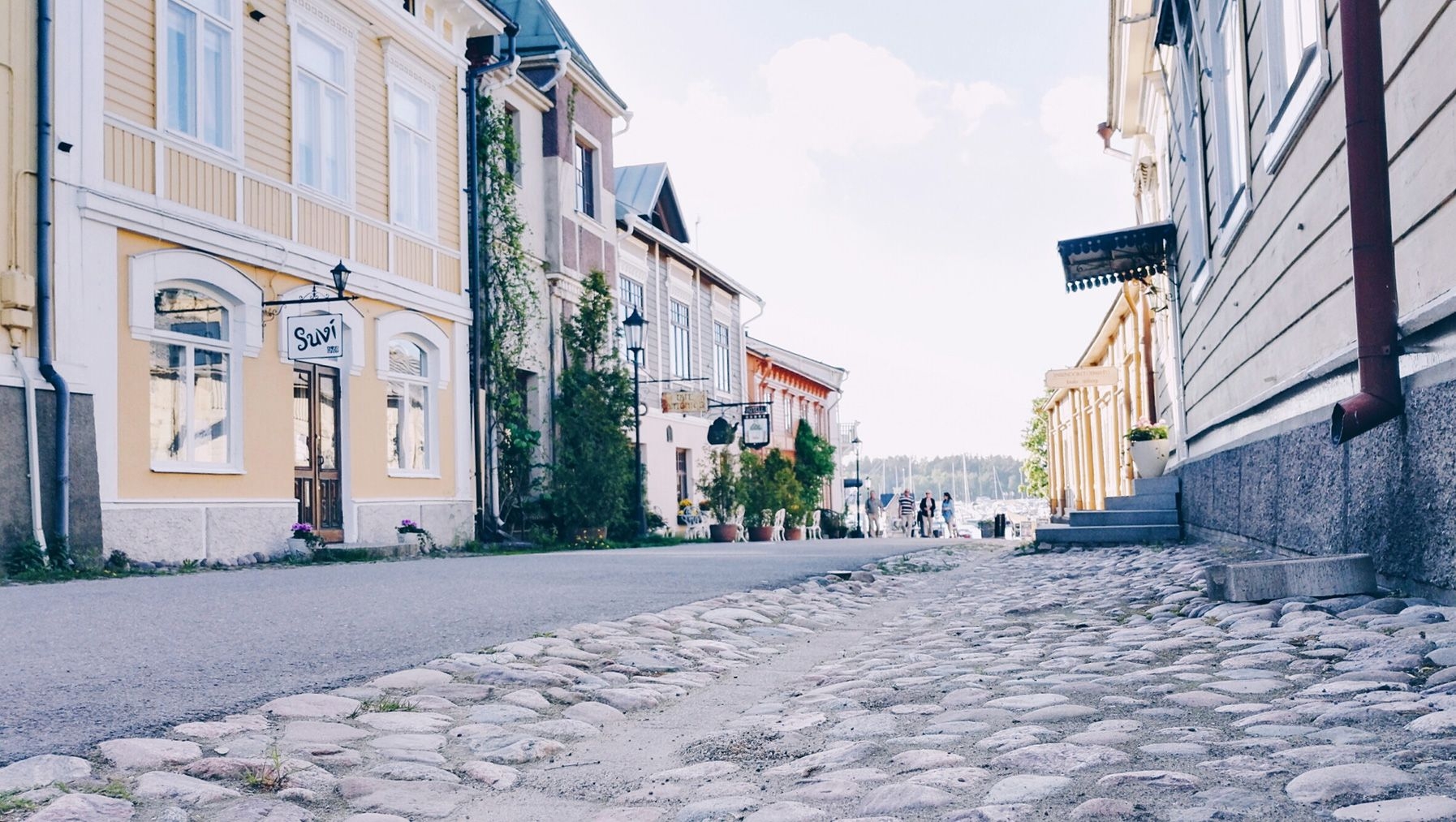 A cobblestone street in Naantali's Old Town, lined with pastel-coloured wooden buildings.