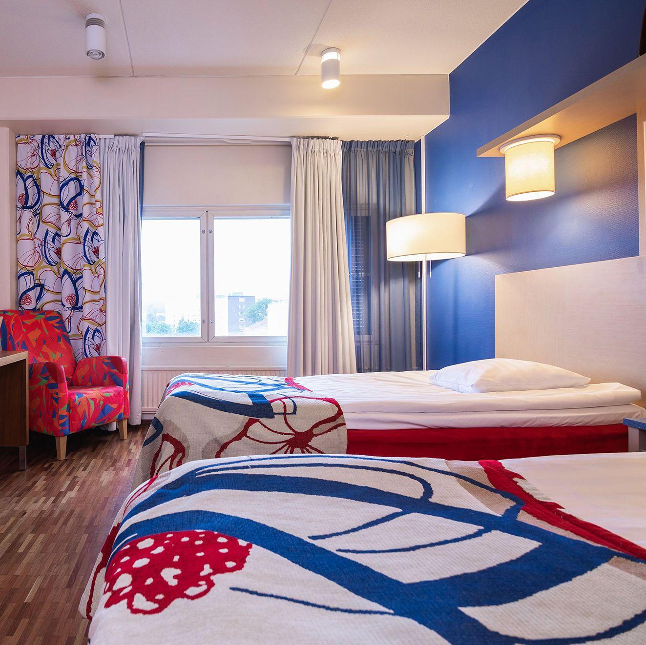 Ett färgglatt sovrum på Scandic Atrium, med två enkelsängar med röda och blå överdrag.