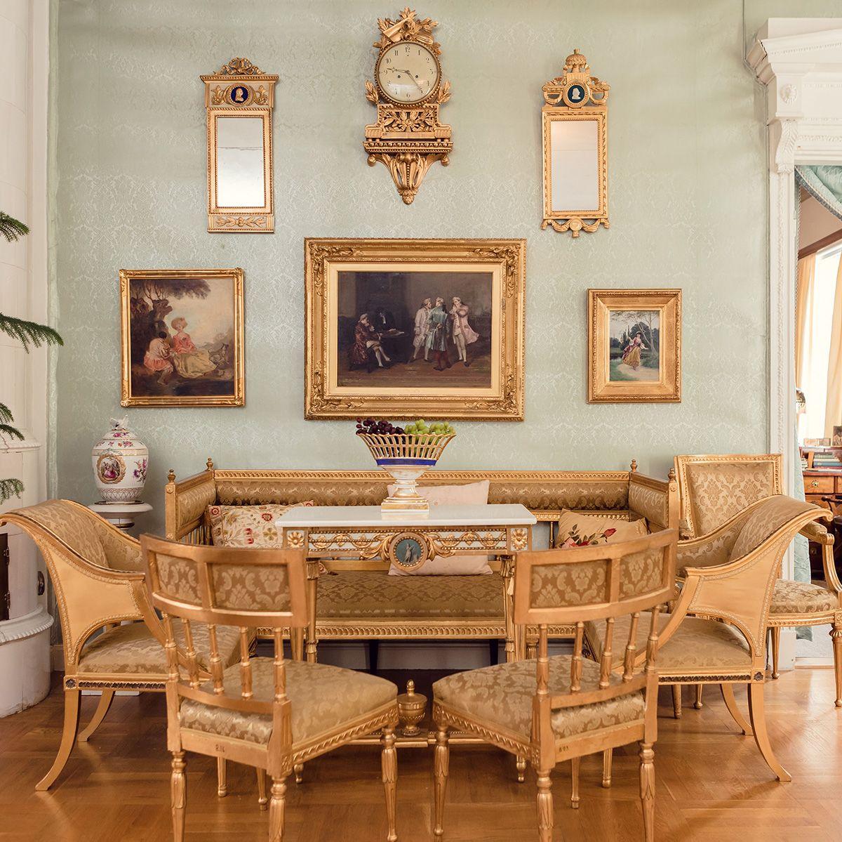An elegant room at Ett Hem, featuring gold-coloured chairs and gold-framed paintings.