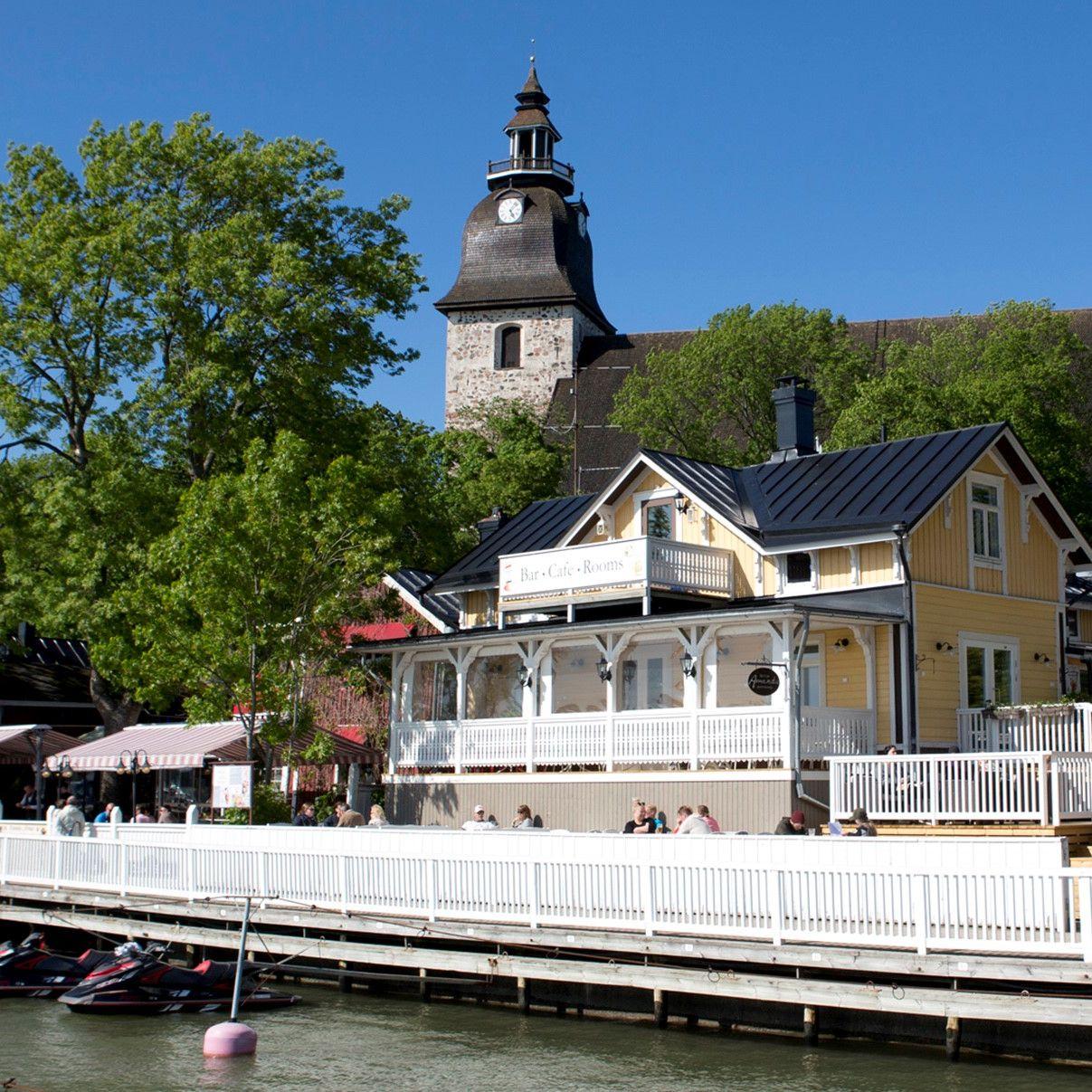 The yellow wooden building of Amandis, featuring the Naantali Church in the background.