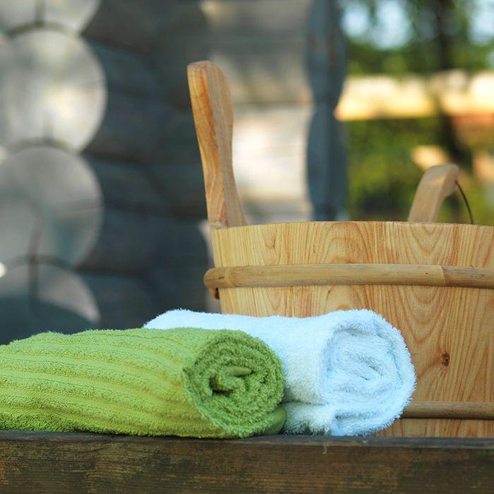 Kaksi pyyhettä ja puinen ämpäri Ruissalon kylpylässä.