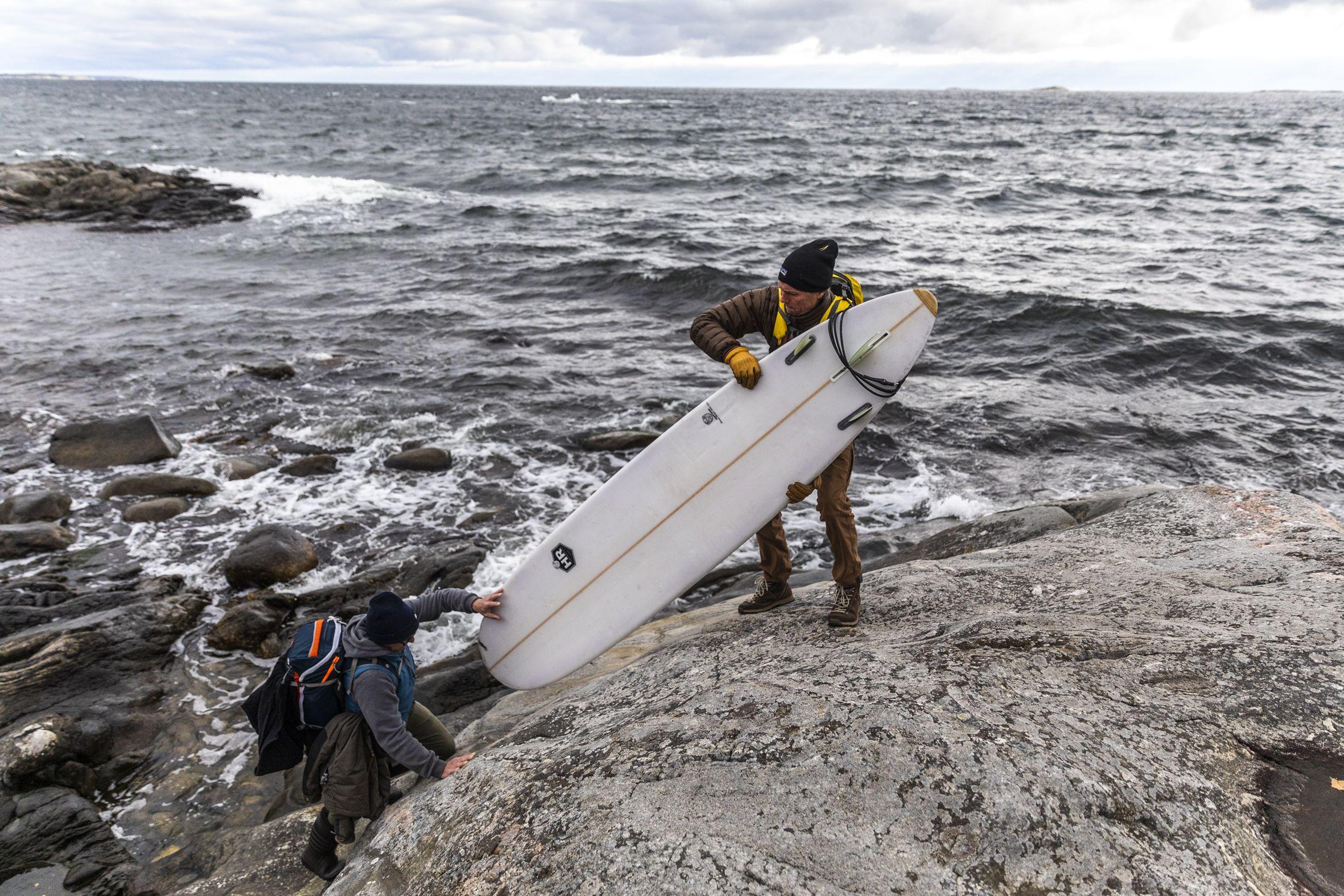 Två surfare lyfter en surfingbräda på Nåttarö. Foto:  Henrik Trygg