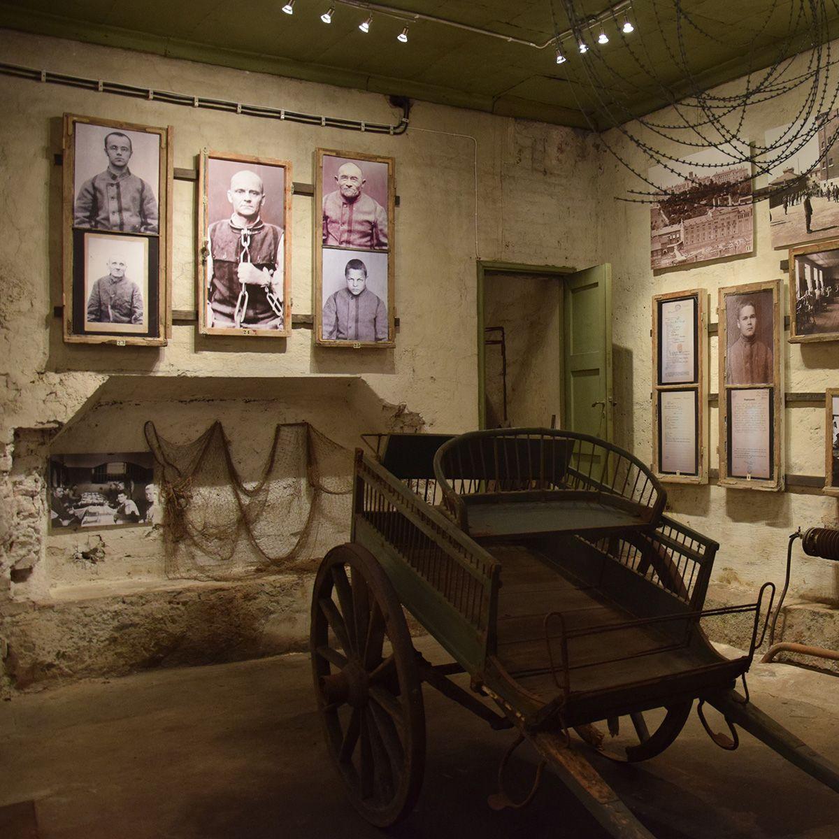 Kakolanmäen museon näyttelytila, jonka seinillä on valokuvia ja katosta roikkuu kettinkejä.