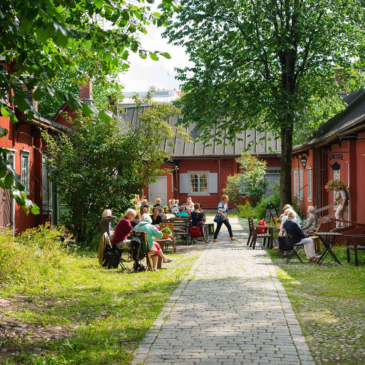Besökare sitter i Cafe Qwensels uteträdgård och njuter av kaffe och kaka.