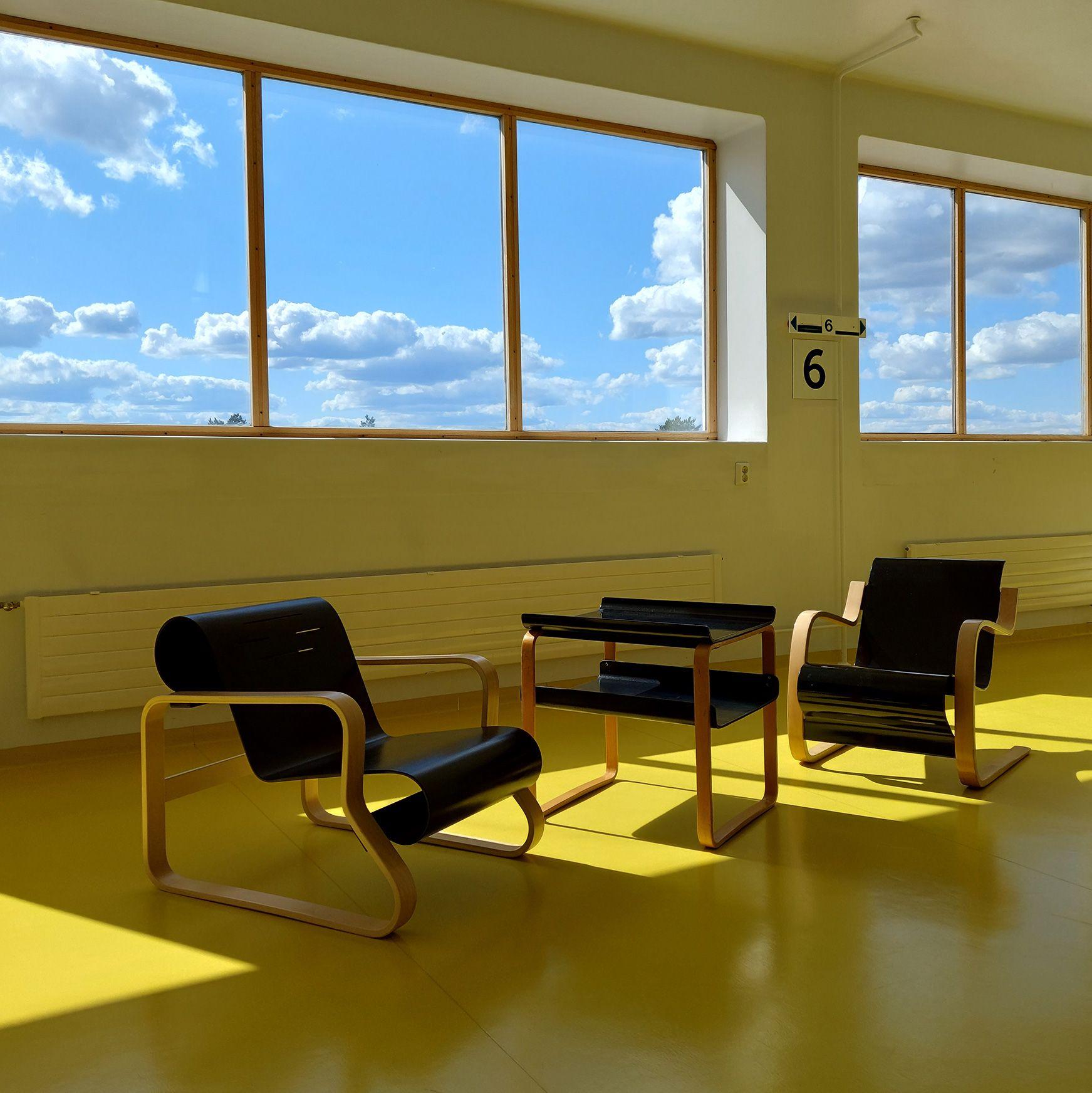 Två stolar och ett bord framför ett fönster på Paimio Sanatorium.