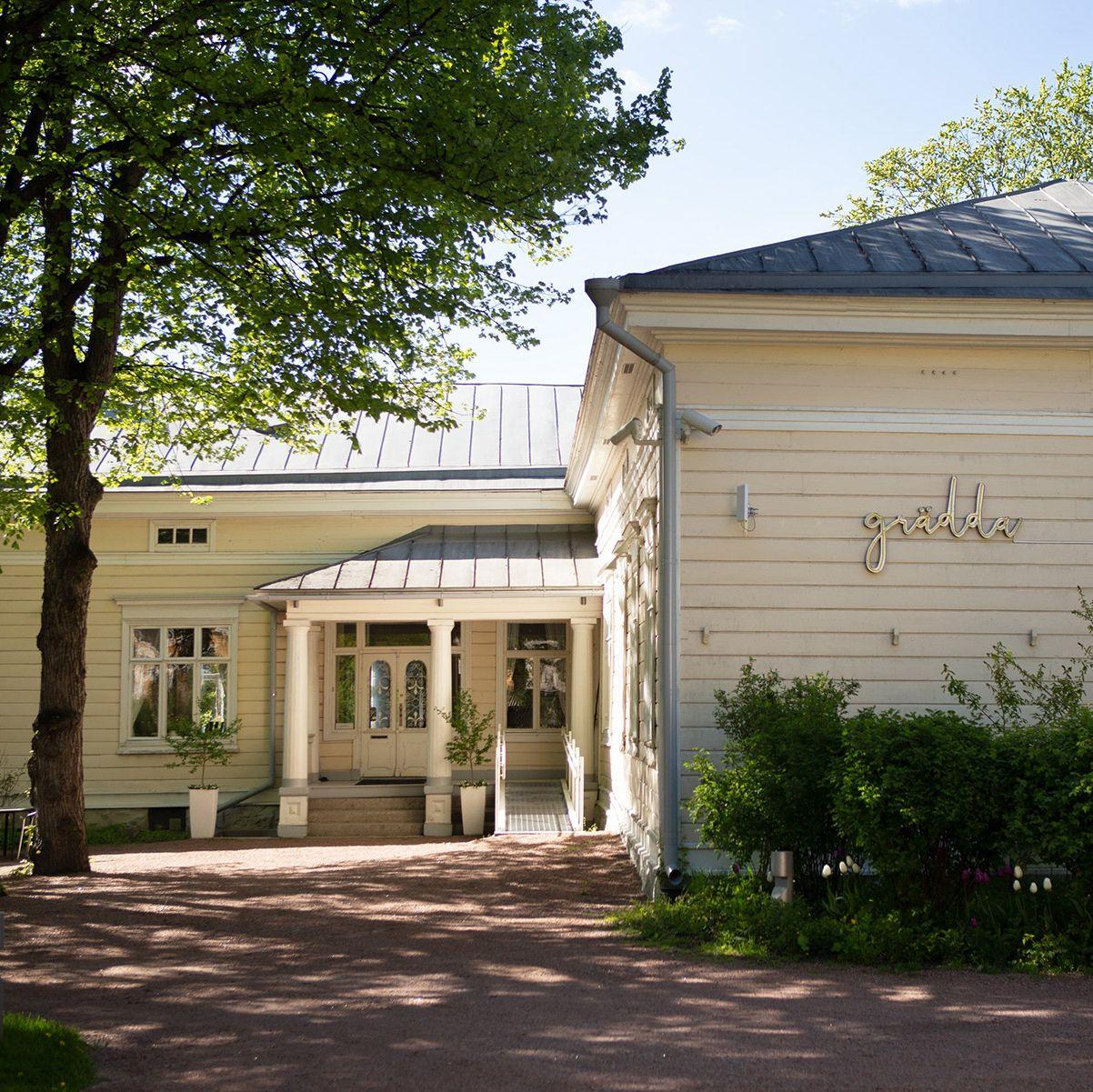 The cream-coloured building of Restaurant Grädda, surrounded by greenery.