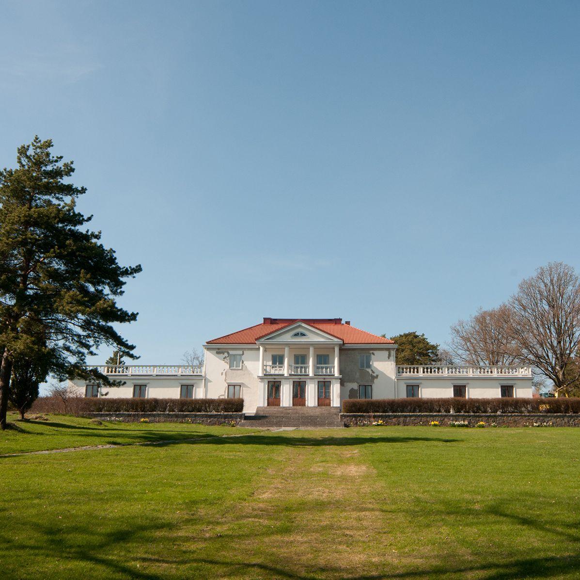 The white building of Söderlångvik Manor on top of a grassy hill.