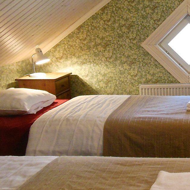 Lanterna Hotelin makuuhuone, jossa on kaksi sänkyä ja salmiakinmuotoinen ikkuna.