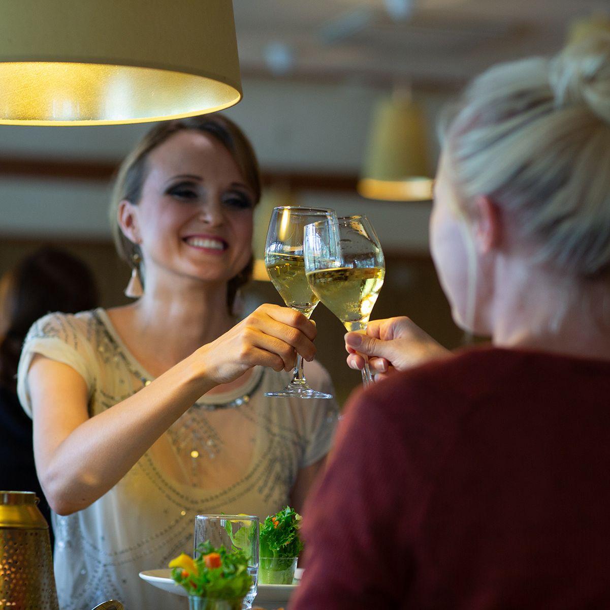 Två kvinnor höjer sina glas vin tillsammans i en skål på Nådendal Spa Hotel and Resort.