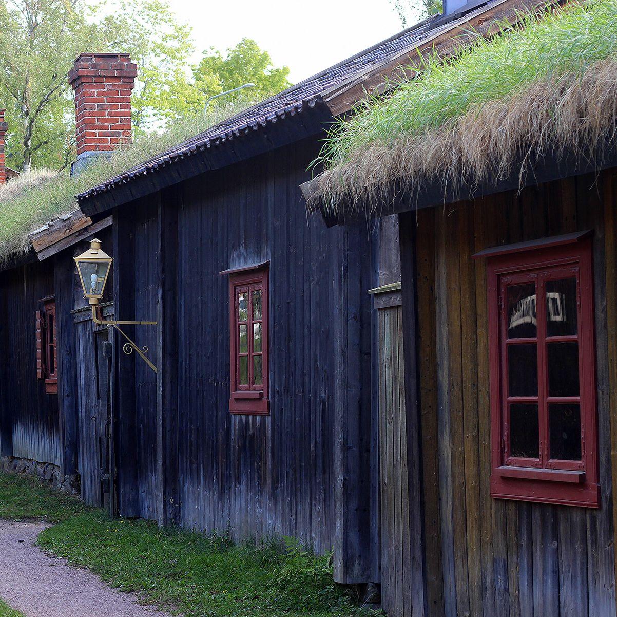 En rad gamla träbyggnader med grästak vid Luostarinmäki.