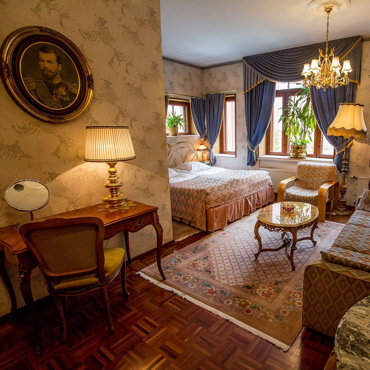 Den eleganta interiören i ett rum på Park Hotel, med målningar, träskrivbord och blå gardiner.