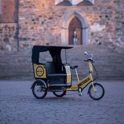 An electric rickshaw operated by Biketaxi Turku. It's yellow and black, and has three wheels.