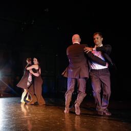 Two couples, part of AB Dance Company, dance on stage.